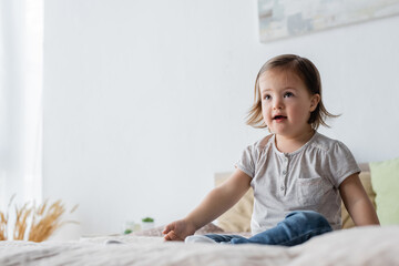 Fototapeta premium Girl with down syndrome looking away on bed at home.