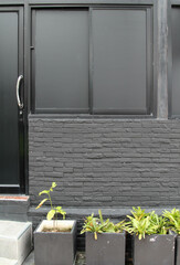 Black aluminum windows and door on gray brick wall.