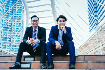 Portrait of business team  sitting on the stairs and consulting about his project.