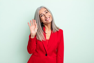 middle age gray hair woman smiling happily, waving hand, welcoming and greeting you. senior...