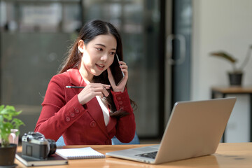 Young Asian happy businesswoman communicating over mobile phone in the office.