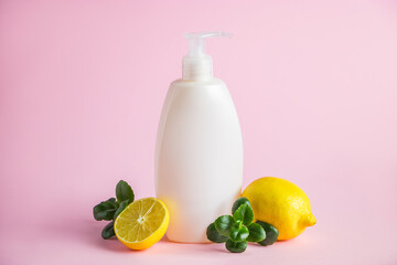 Organic cosmetics with lemon oil. Bottle of moisturizer with citrus on a pink background.