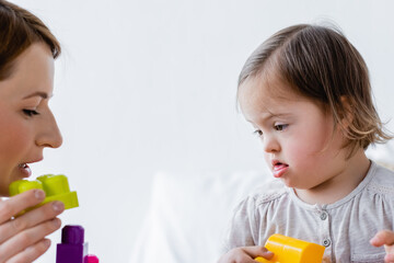 Parent and kid with down syndrome playing building blocks at home.