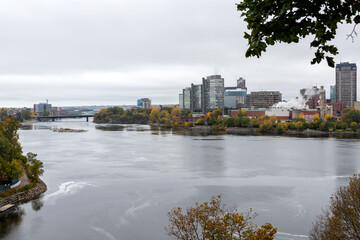 Fototapeta na wymiar Panoramic view of Ottawa River and Gatineau city of Quebec in Canada. Portage Bridge. View from Major's Hill Park in fall season with colorful trees changing colors