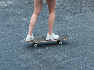 The girl rides a skateboard. Legs and skateboard close up.