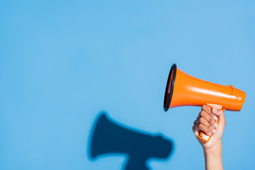 cropped view of african american woman holding orange megaphone on blue