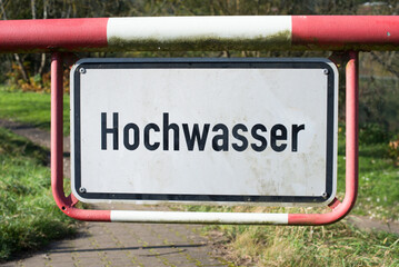 High water sign in german language, next to the river Moselle in Trier, warning for flood, climate...