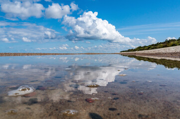 Reflection of clouds in the water. Beautiful sky. The sea coast. Deserted seashore.