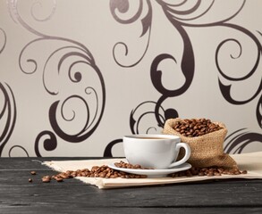 Coffee beans with a cup of hot coffee on wooden desk