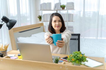 A photo of a bright Asian woman working at home, in the bedroom. The idea is: Workform Home, Finance, Marketing, Bright, Portrait, Simple.