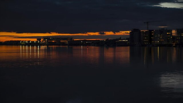 Sun setting down over Antwerp buildings and river Schelde with water reflections, vibrant shot