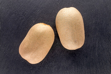 Two ripe sweet kiwi fruits on a slate stone, close-up, top view.