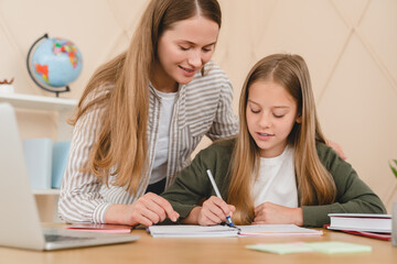 Young caucasian teacher mother tutor babysitter nanny helping her daughter schoolgirl student with...