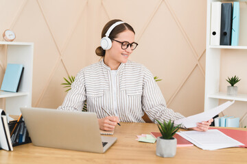Young smart businesswoman teacher student freelancer designer listening to the music in headphones...
