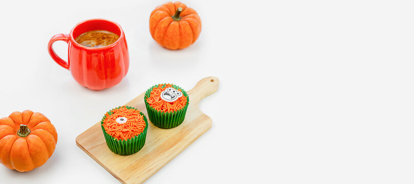 orange cup of coffee, pumpkins and cupcakes on white background for Halloween