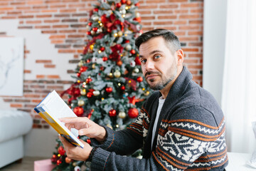 A man with a beard at home relaxing and reading a book, a businessman on Christmas and New Year...