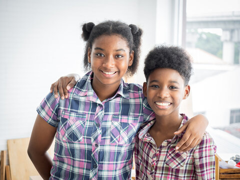 Two African American Brothers And Sisters Hug The Neck And Look Camera's Smile. Older Sister Hugs Little Brother By The Neck.