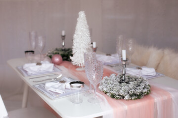 Beautiful Christmas dinner setting. Festive table setting with a tablecloth among winter...