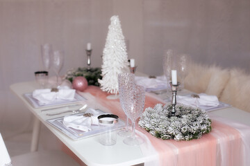 Beautiful Christmas dinner setting. Festive table setting with a tablecloth among winter decorations and white candles. Top view, flat lay. The concept of Christmas or New year family dinner.	
