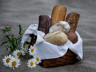 Still life of different types of bread baguettes in a wicker basket and a delicate bouquet of...