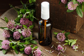 Red clover tonic water or lotion on wooden rustic background, herbal plant is used as immune,...