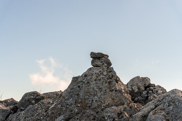 Selective focus to some large rocks stacked in balance against the blue sky in the background.