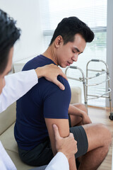 Fototapeta na wymiar Vertical shot of unrecognizable professional physiotherapist examining sporty young man palpating his shoulder