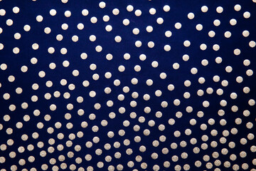 Golden dots on a dark background. Dark blue background with polka dots, fabric texture with a pattern.
