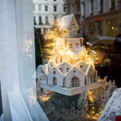 Homemade gingerbread house and Christmas spices with ornament. Reflections in a shop window