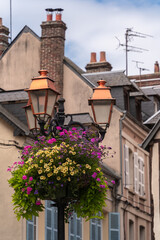 Fototapeta na wymiar Street lamp decorated with flowers and old town buildings in Honfleur, Normandy