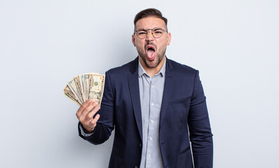 young handsome man feeling disgusted and irritated and tongue out. dollar banknotes concept