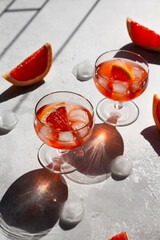 Glasses of ice cold Aperol spritz cocktail served in a wine glass, decorated with slices of grapefruit. Hard light