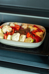Cooking meat with vegetables in oven. Prepare raw ingredients for healthy dinner idea recipe. Pork steak with bell peppers, zucchini and cauliflower. Stew cooking
