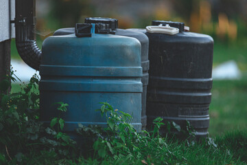 three plastic barrels near house wall