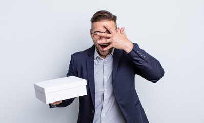 young handsome man looking shocked, scared or terrified, covering face with hand. white box concept