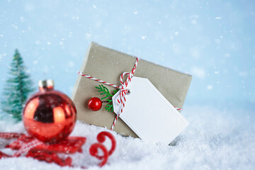 Christmas presents with white label, wrapped with craft paper on snow