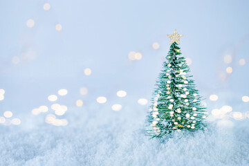 Christmas tree with christmas lights on white snow against bokeh background