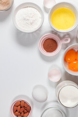 Baking ingredients: flour, eggs, sugar, butter, milk and spices on white background. Top view, flat lay, copy space