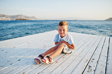 Boy sit at Turkey resort on pier against Mediterranean sea.