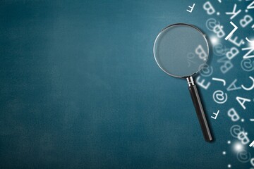 A magnifying glass with part of scattered English alphabet letters on the desk background - obrazy, fototapety, plakaty