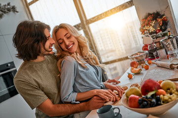 Sensual romantic couple preparing cookies together in the kitchen on Christmas Eve.