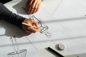 Clothing designer draws sketches on paper in the workplace. The artist creates a model for the dress. Fashion concept.