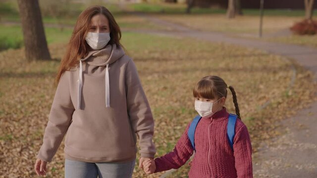 Mom Little Child With Backpack Walking Around Schoolyard Wearing Medical Masks, Mother Kid Rushing Merrily School Class For Lesson, Childhood Protected From Coronavirus Pandemic, Covid 19, First Grade