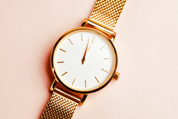 Gold coloured feminine wrist watch on a pink background. Just before 12 O' clock. New year concept....