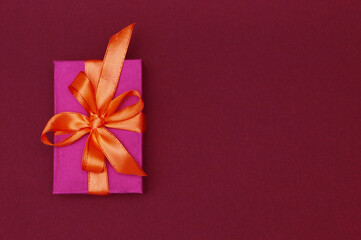 Red gift box with bow on paper background.