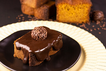 Carrot and chocolate cake with chocolate cream and brigadeiro on black plate