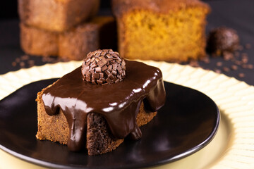 Carrot and chocolate cake with chocolate cream and brigadeiro on black plate