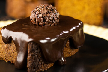 Carrot and chocolate cake with chocolate cream and brigadeiro on black plate