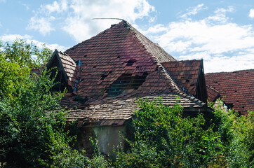 Fototapeta na wymiar Roof of an old abandoned house with broken and fallen tiles