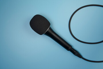 Concert microphone connected by cable on a blue background. Close up. Copy space